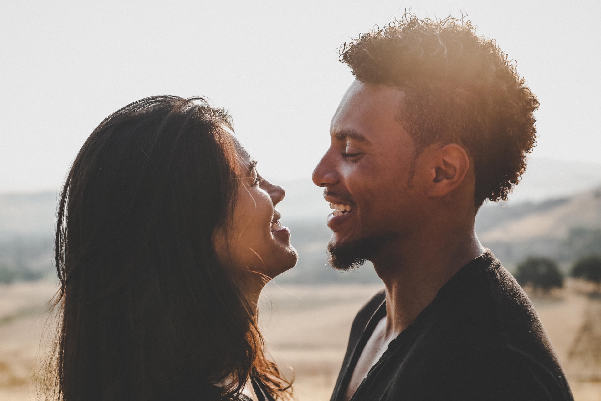 Man and woman looking at each other with the beach in the background.