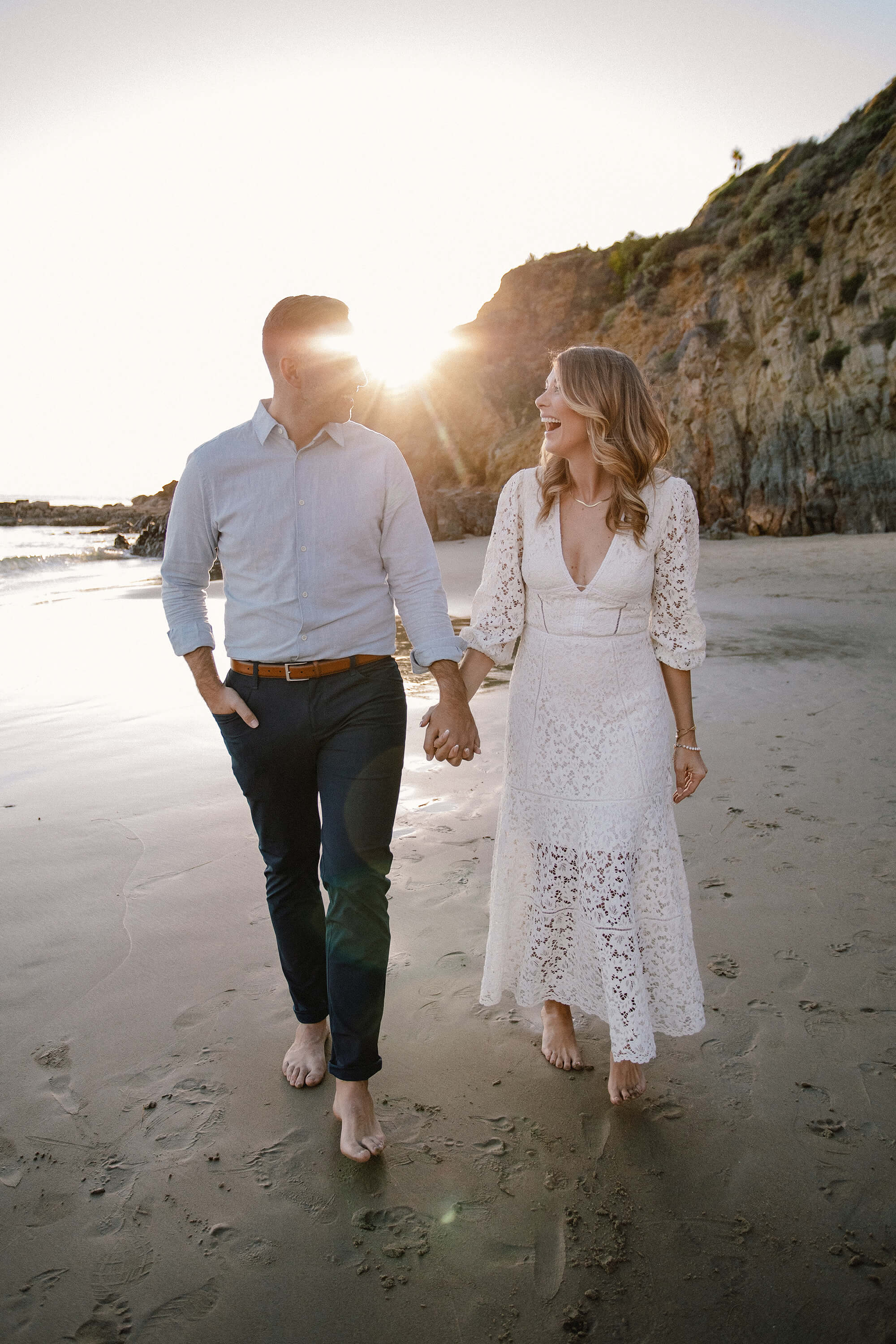 JJ and Kait holding hand walking on the beach.